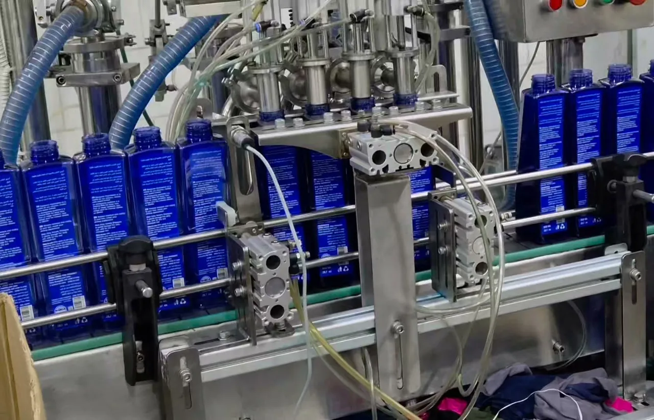 Four-nozzle filling station dispensing shampoo into blue bottles on a conveyor