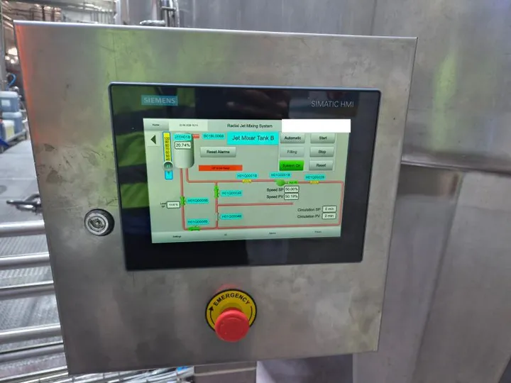 Siemens SIMATIC HMI in a stainless-steel enclosure with an emergency stop, showing a jet mixer tank, valves, the pump speed setpoint and actual value, and circulation time