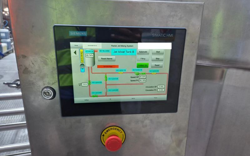 Siemens SIMATIC HMI in a stainless-steel enclosure with an emergency stop, showing a jet mixer tank, valves, the pump speed setpoint and actual value, and circulation time