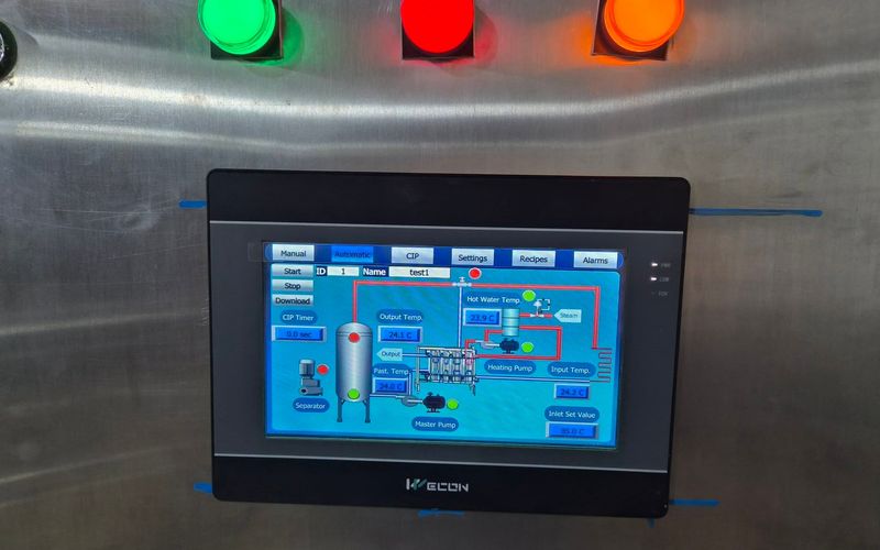 Wecon HMI on a stainless-steel cabinet showing the pasteurizer process, with tabs for Manual, Automatic, CIP, Settings, Recipes and Alarms