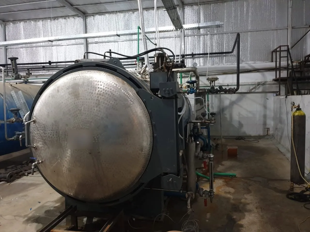 Horizontal olive sterilization autoclave with a round stainless-steel door in a processing hall