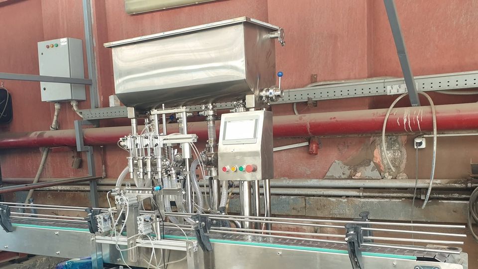 Four-nozzle piston filling machine with a stainless-steel hopper, conveyor and operator push-button box