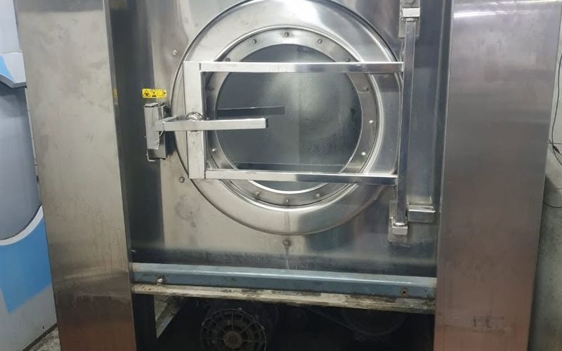 Stainless-steel front-loading washer-extractor in a hotel laundry room