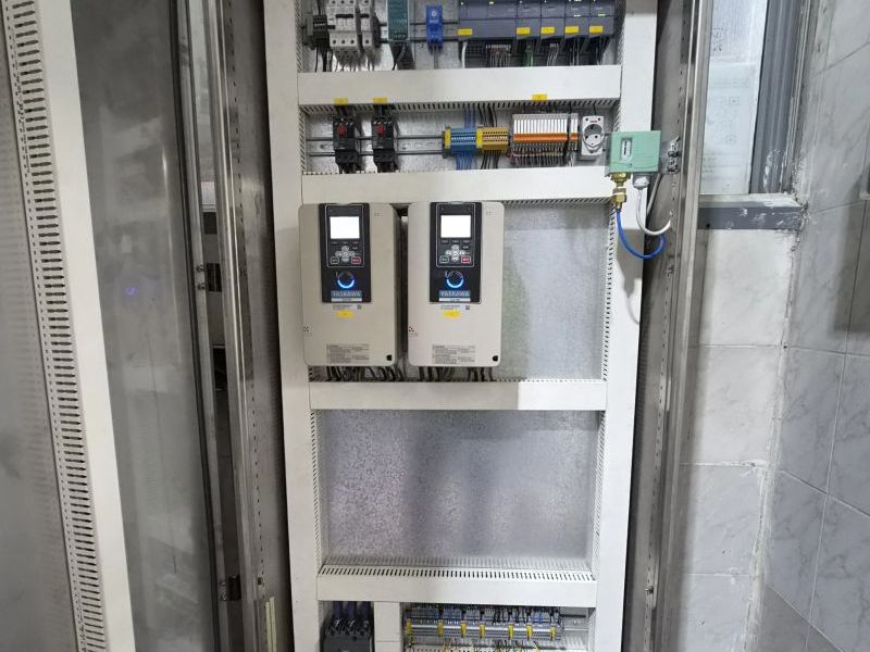 Control panel with two Yaskawa drives, a Siemens S7-1200 PLC with I/O modules, a power supply, circuit breakers, relays, terminals and a pressure switch