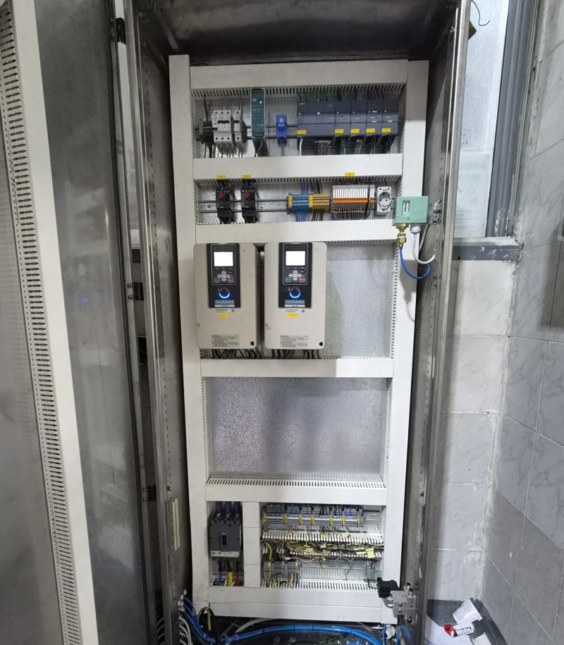 Control panel with two Yaskawa drives, a Siemens S7-1200 PLC with I/O modules, a power supply, circuit breakers, relays, terminals and a pressure switch